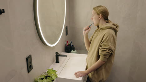 teenager brushing teeth in modern bathroom