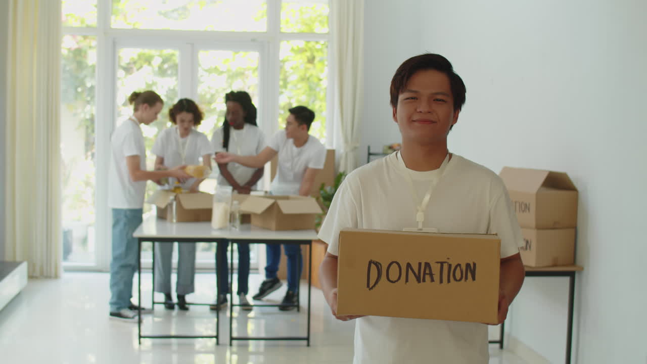 Asian Male Volunteer with Donation Box in Charity Office Organization