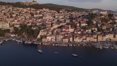 drone view of sibenik with small boats at harbour during sunrise, aerial