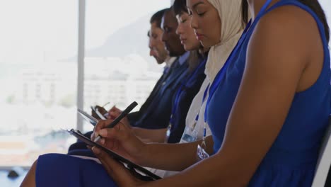 women in the audience at a business seminar writing