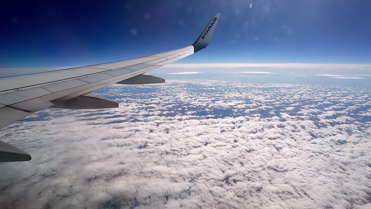 A Smooth Point Of View Shot Of An Airfoil From A Porthole Of An Aircraft Above A Cloudscape