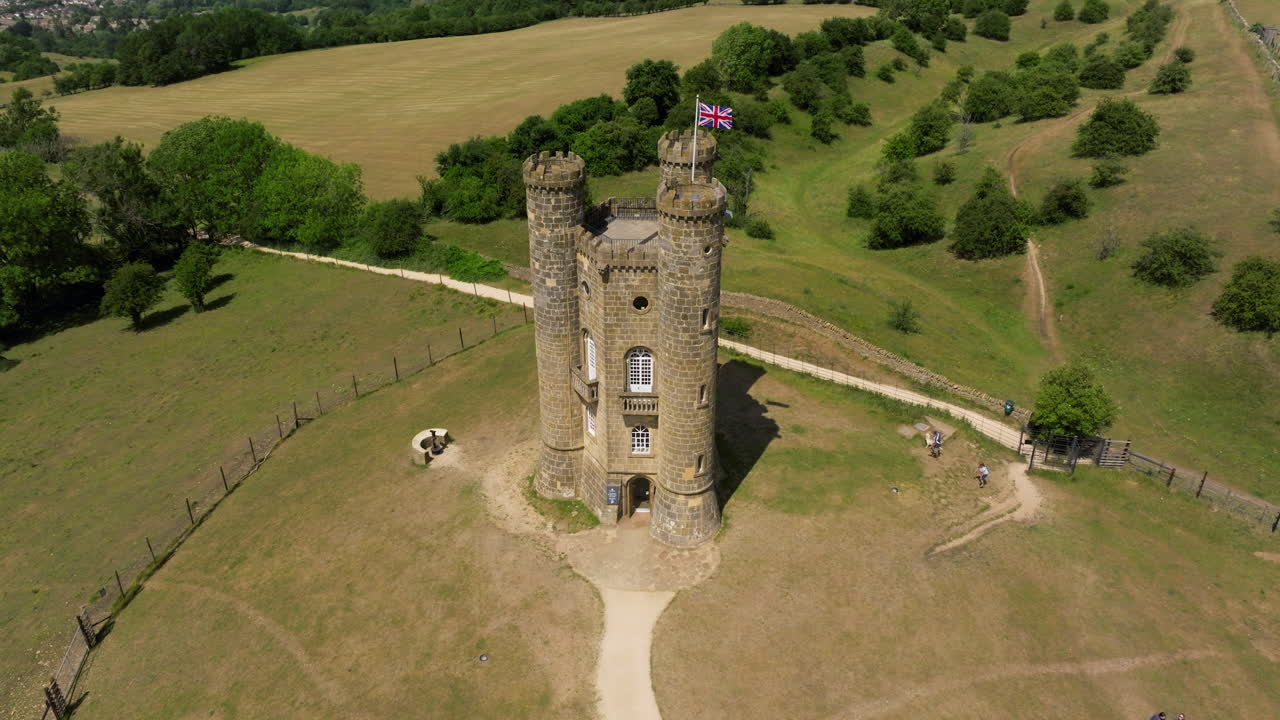Broadway Tower Over Cotswolds Escarpment In Broadway, England, United Kingdom. Aerial Ascending Shot
