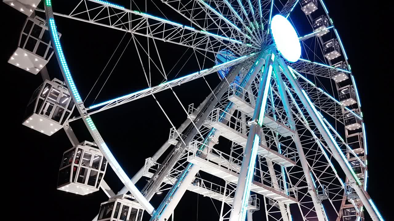 низкоугольный вид металлического колеса обозрения, освещенного на ночном небе