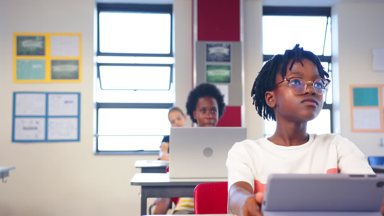A scuola, studentesse che usano laptop e tablet in classe, concentrate sull'apprendimento.