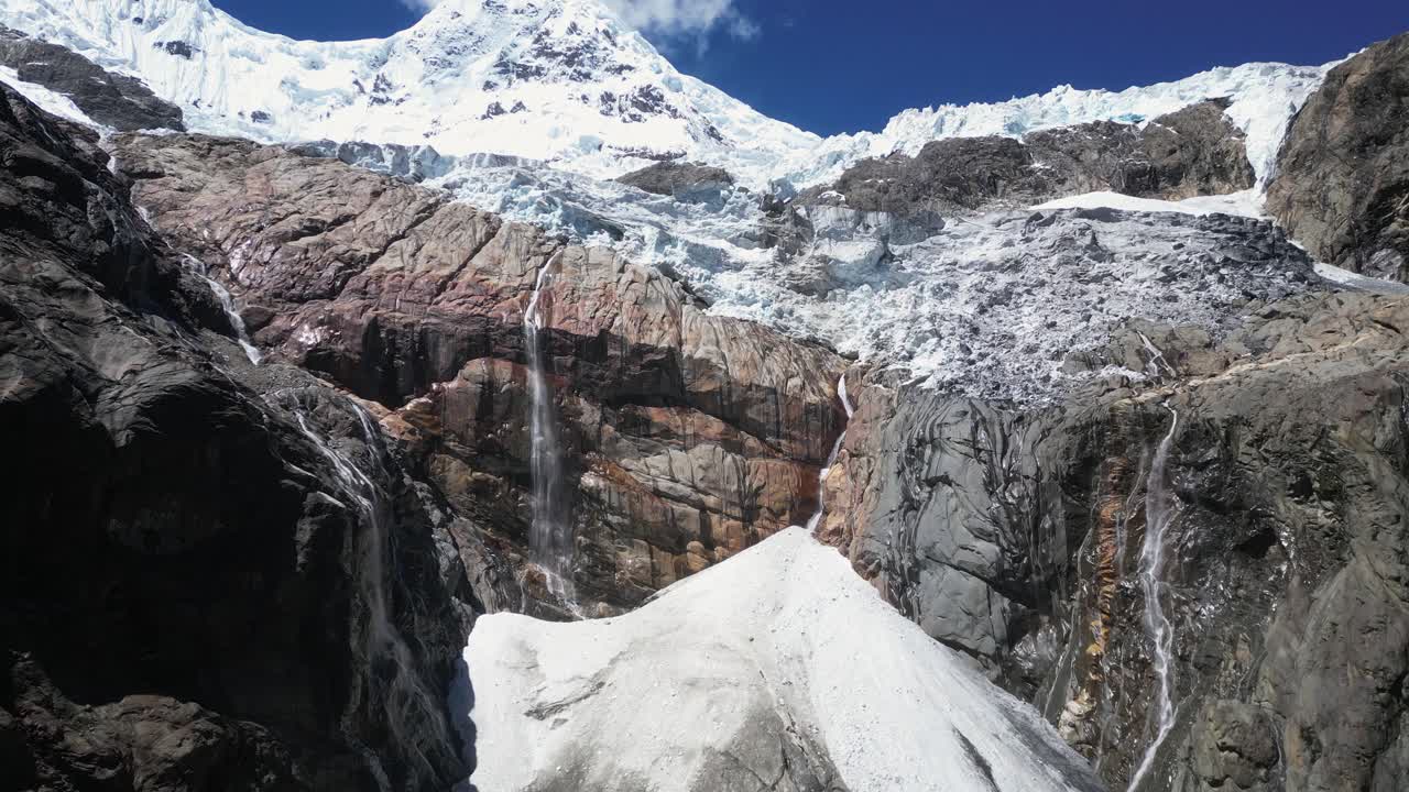 Snow dome and rock cliff waterfalls below icy mountain glacier, Peru