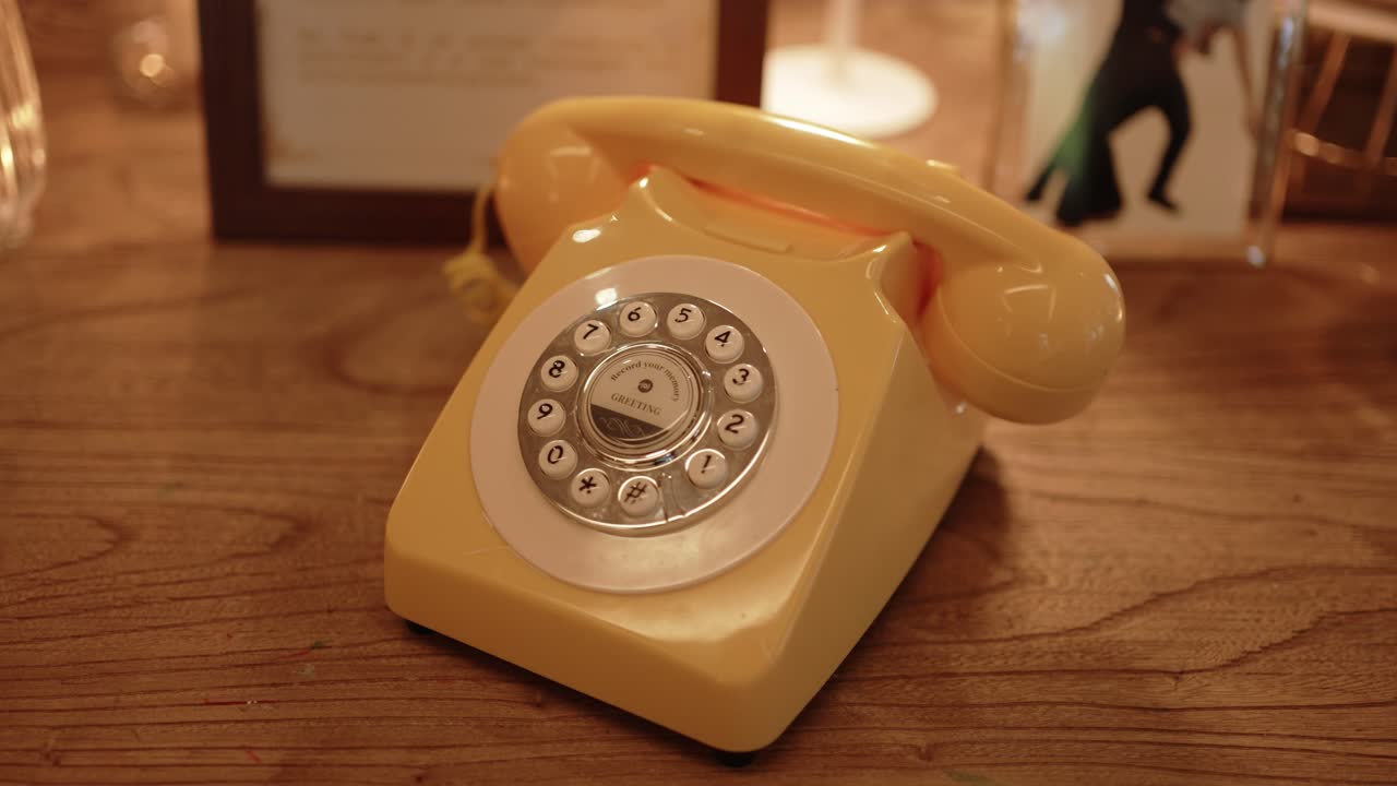 Retro yellow rotary phone adds charm to wedding decor on rustic wooden surface