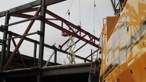 construction site with steel framework, workers, and heavy machinery