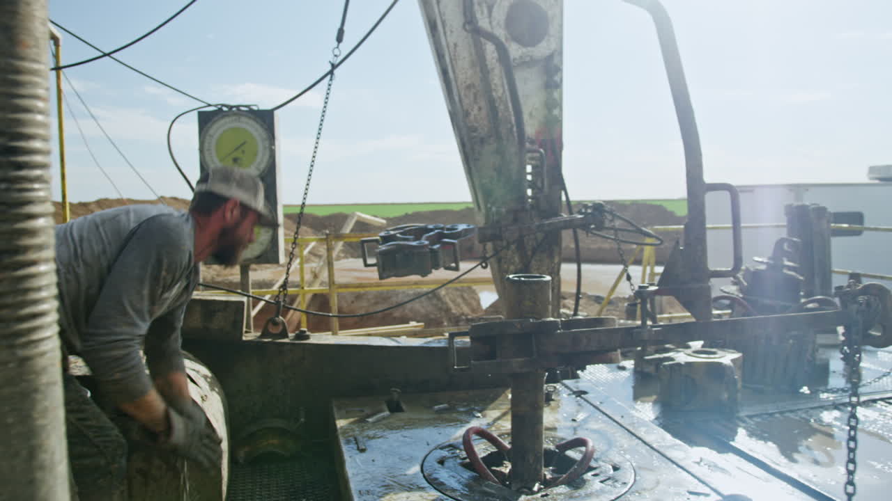 Site for production natural resources in the desert. Man works at the location setting the equipment for drilling.