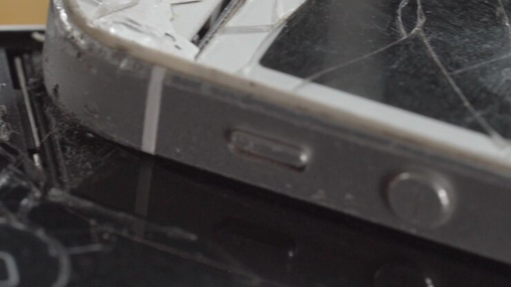 Closeup of cracked smartphone screen with shattered glass and visible impact damage. Broken mobile device highlighting repair, accident, technology failure, and maintenance