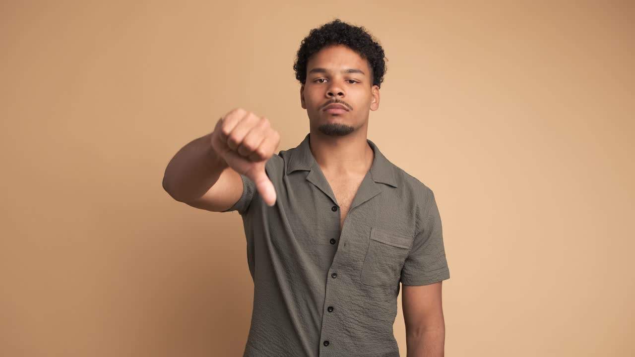 Sad man making thumbs down sign and shaking head in displeasure