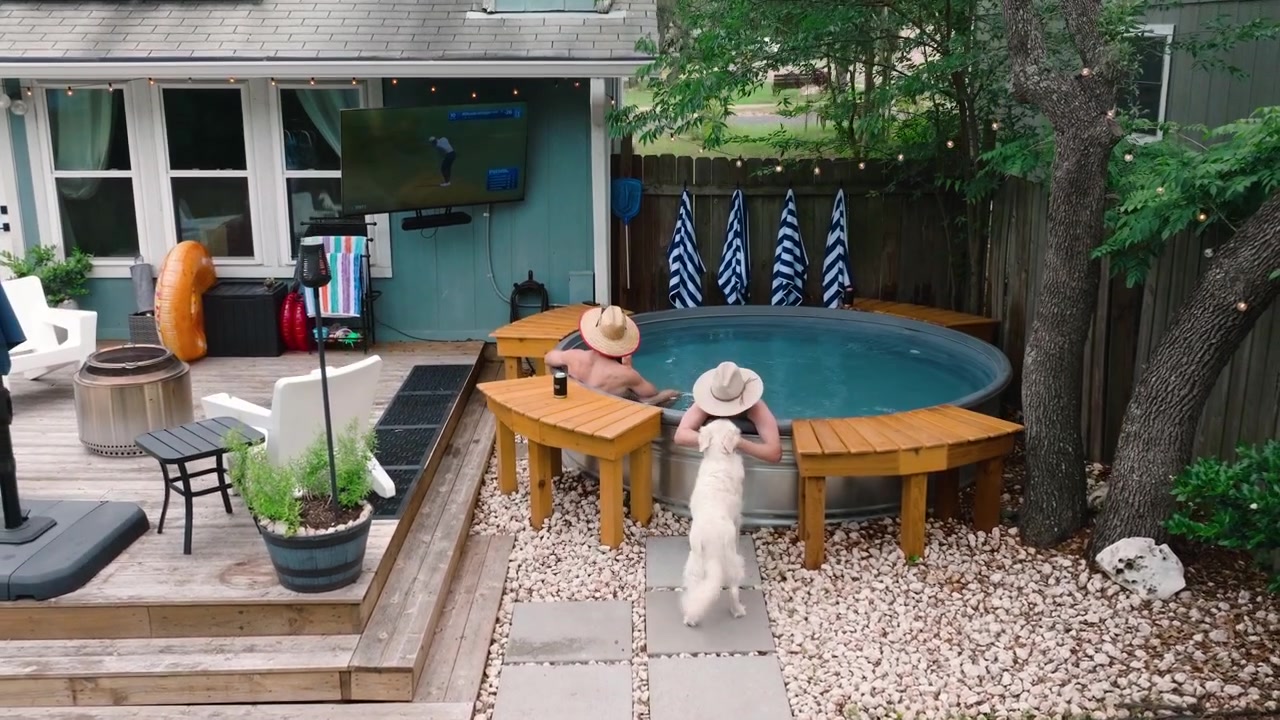 Couple relaxing in a backyard hot tub with sun hats petting dog, watching golf. Outdoor luxury lifestyle, dream home summer content