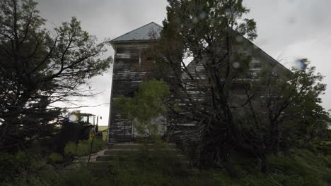 abandoned farm house in stormy weather rain and trees swaying