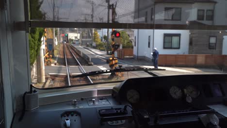 view inside the cabin of a japanese train driving through the narrow tracks at the stoplight in japan - wide shot
