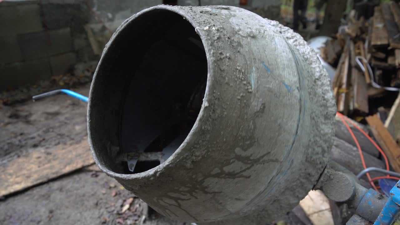Worker pouring water into cement mixer