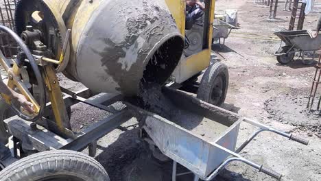 concrete mixer pouring wet cement into the wheelbarrow