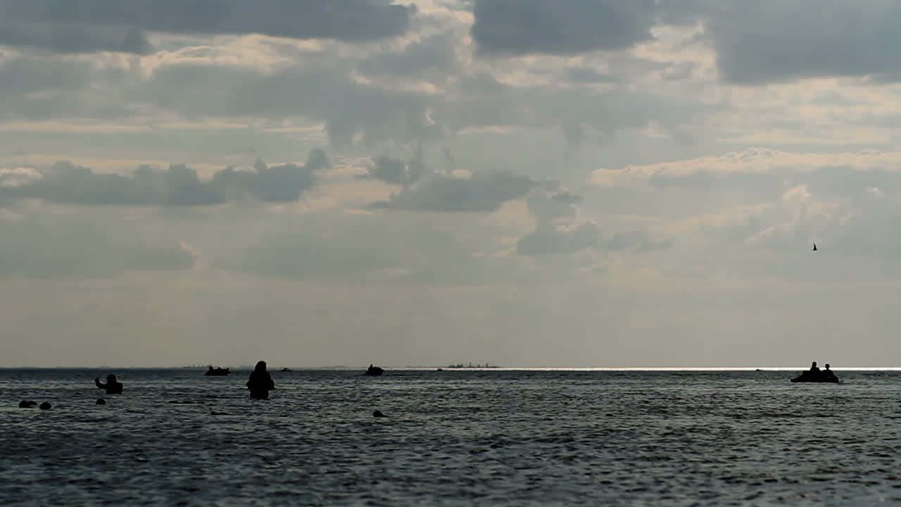 People Having Fun In Ocean Water. Group of people swim in ocean at sunset
