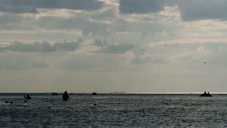 People Having Fun In Ocean Water. Group of people swim in ocean at sunset