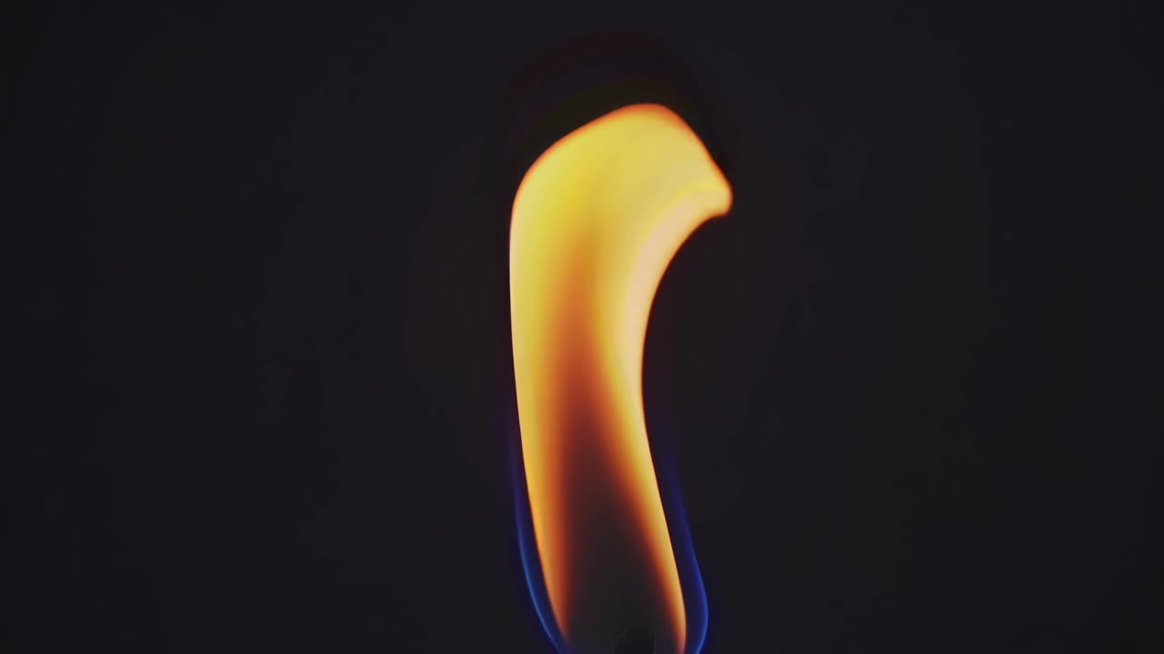 Close-up video of a single flame against a dark background, captured from a side angle