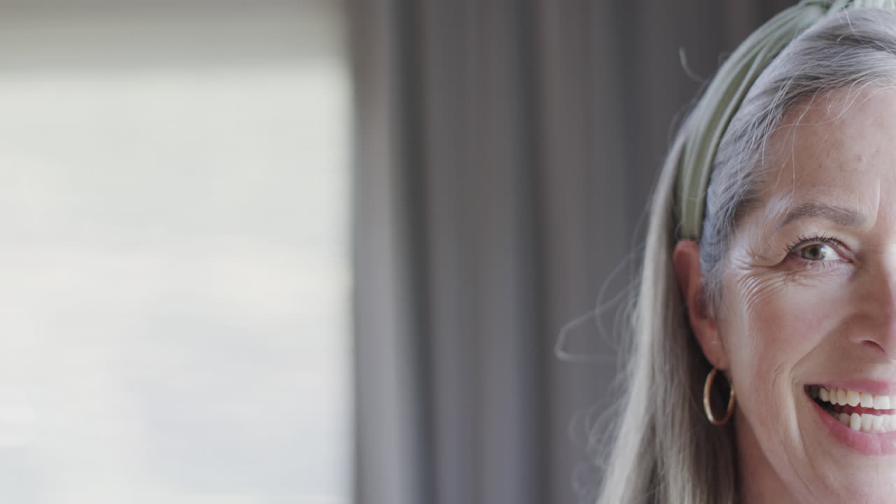 Portrait of middle aged happy caucasian woman by window at home with copy space