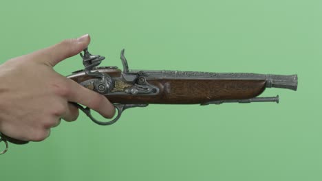 hand holding antique pistol on green screen