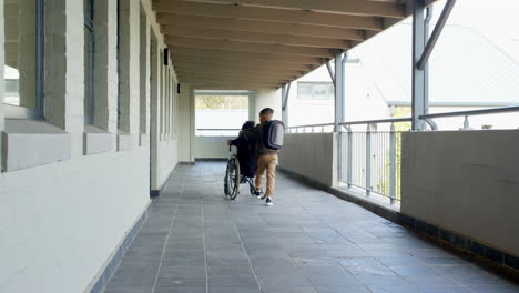 boy pushing wheelchair down school hallway, showing kindness and support
