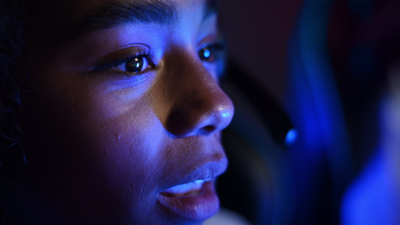 Close view of a black teen smiling girl playing video games in video game club with blue illumination. Slow motion