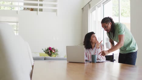 Mujer-Birracial-En-Silla-De-Ruedas-Y-Pareja-Masculina-Tomando-Café-Y-Usando-Una-Computadora-Portátil-En-La-Sala-De-Estar