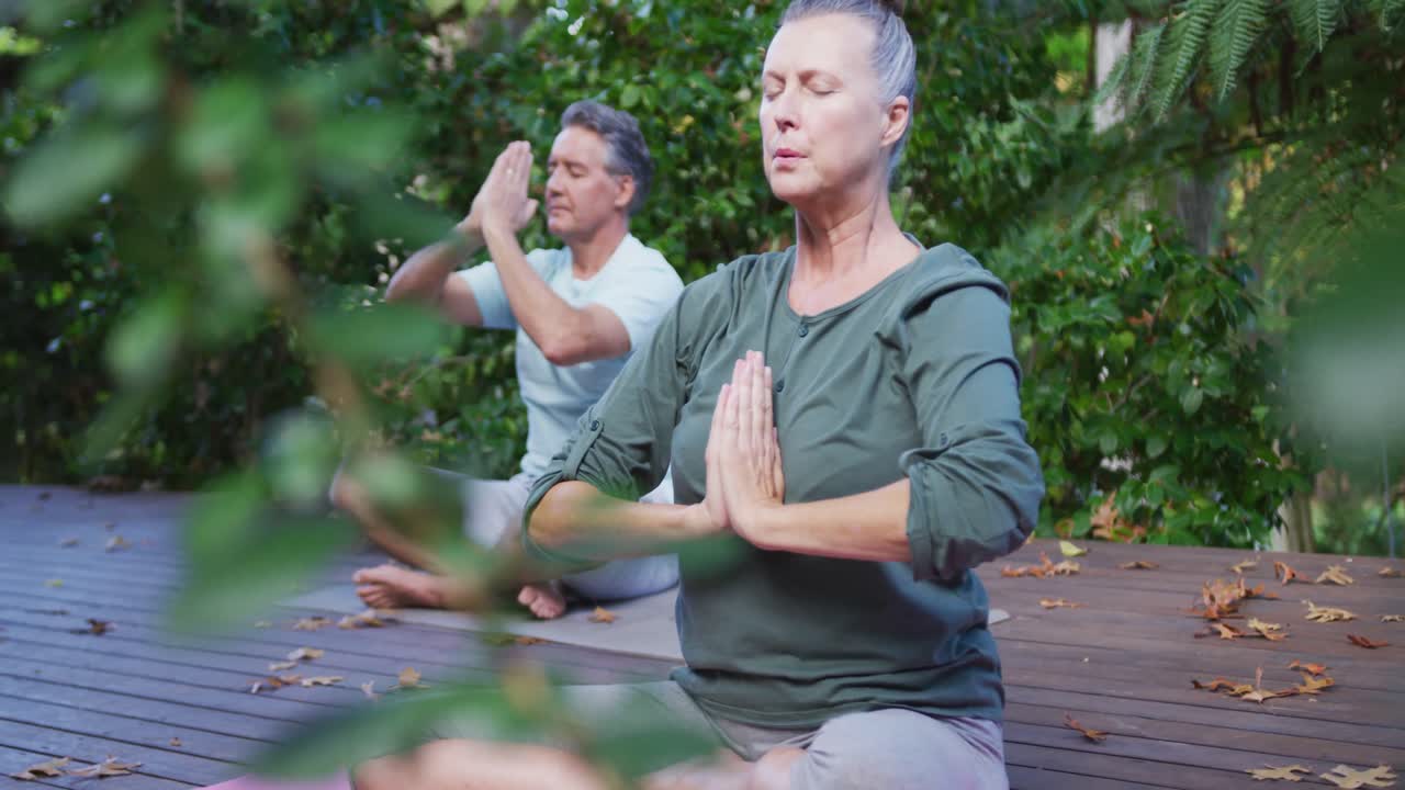 relajada pareja caucásica feliz practicando yoga juntos, meditando sentados en el jardín