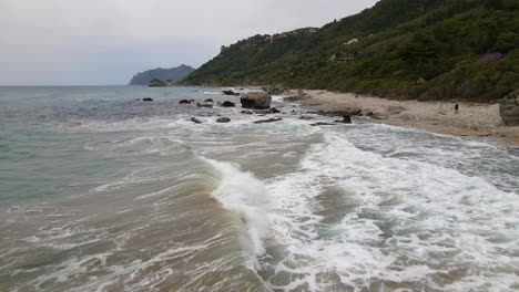 Aerial,-low-flight-over-sea-waves-crushing-on-rocky-beach-in-slow-motion