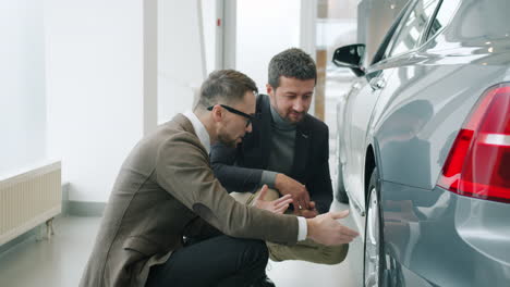 car salesman showing car details to customer