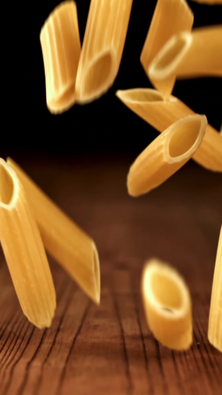 Penne che cadono al rallentatore su un tavolo di legno
