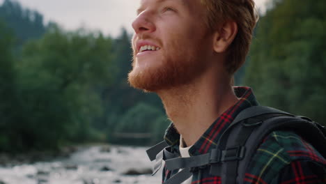 happy guy holding photo camera. redhead man enjoying mountain landscape