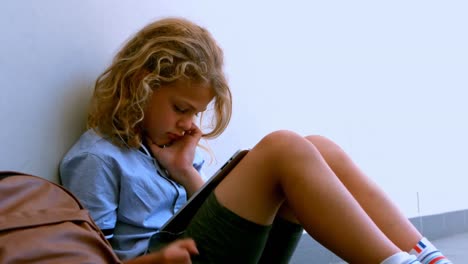Cute-Caucasian-schoolgirl-sitting-on-floor-and-using-digital-tablet-in-school-corridor-4k