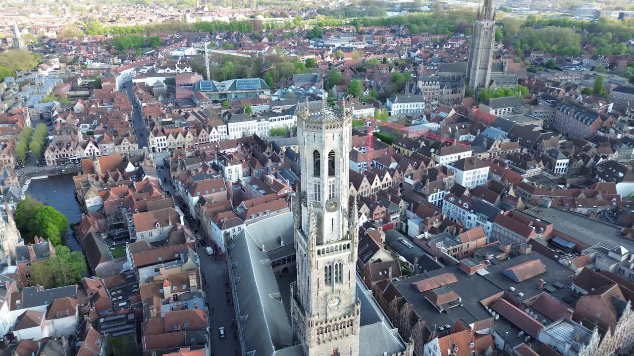 Spettacolare ripresa aerea con drone della Torre del Belfort di Bruges. Visione cinematografica a volo d'uccello della storica Piazza del Mercato, dei tetti medievali e delle strade acciottolate in Belgio.