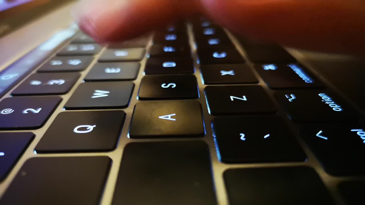 primer plano de los dedos escribiendo en el teclado del portátil y desplazándose y haciendo clic en el trackpad