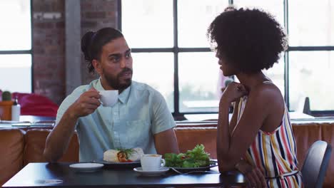 diverse male and female colleagues sitting in cafe drinking coffee having a discussion