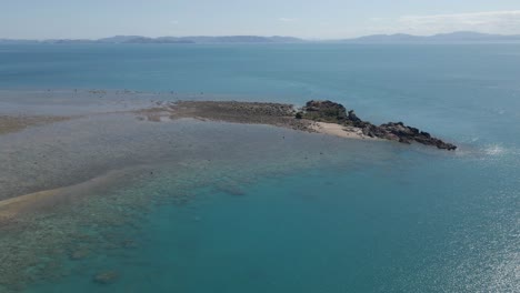 agua cristalina de mar azul con isla de pájaro rocoso - paisaje marino en la isla de whitsunday en qld, australia