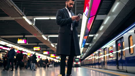 Man Using Smartphone While Waiting for Train at Subway Station