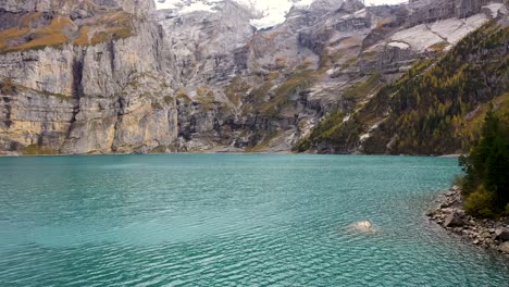 ascending aerial shot of mountains at turquoise glacier lake oeschinensee