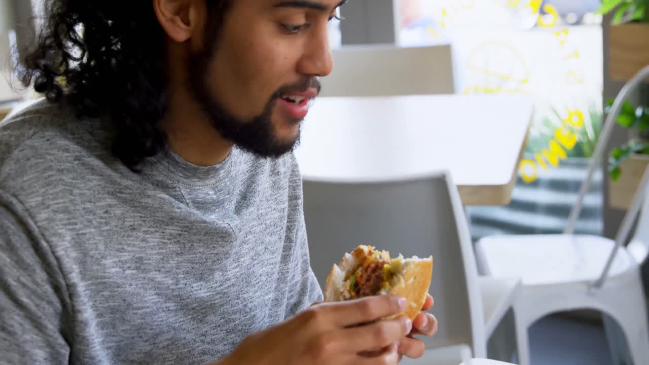 hombre comiendo una hamburguesa en un café 4k