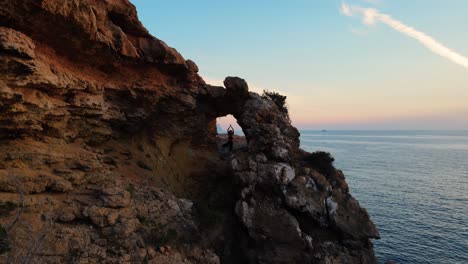 Unrecognizable-girl-doing-yoga-among-rock-cliffs-on-the-seafront
