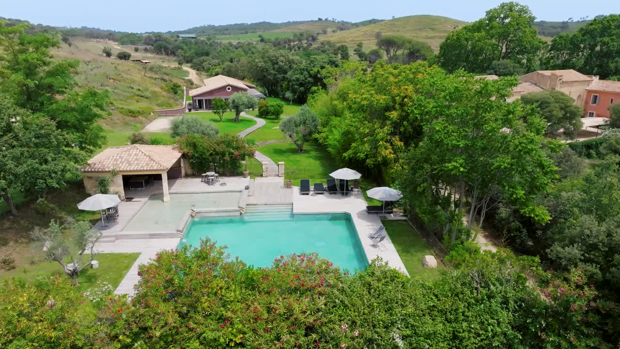 Slow establishing shot of a tropical swimming pool with a villa in France