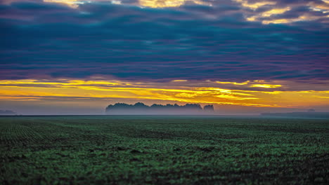 Ein-Goldener-Sonnenaufgang-Eines-Ländlichen-Ackerlandes-Mit-Einer-Wolkenlandschaft-In-Verschiedenen-Richtungen-Aufgrund-Einer-Gedankenscherung---Zeitraffer