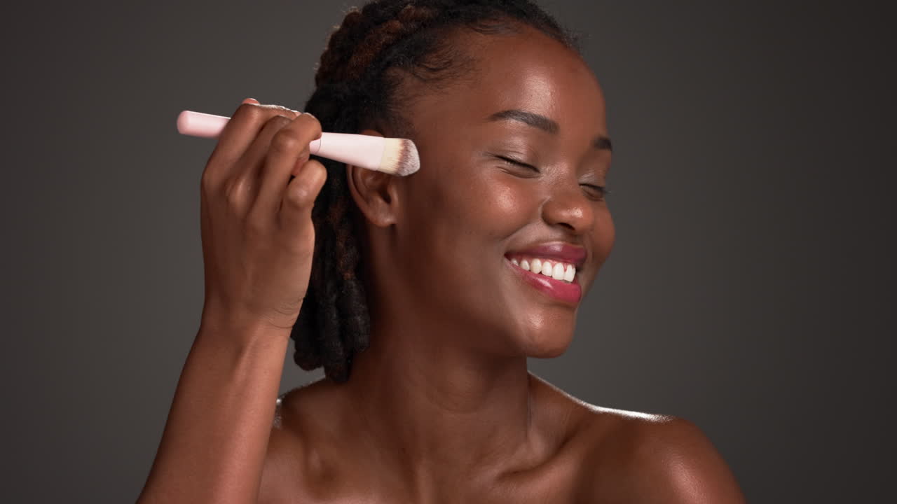 African American woman applying makeup with a brush