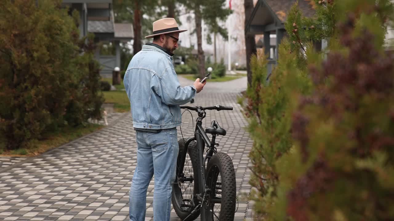 Man looking at phone next to his fat tire bike near resort houses