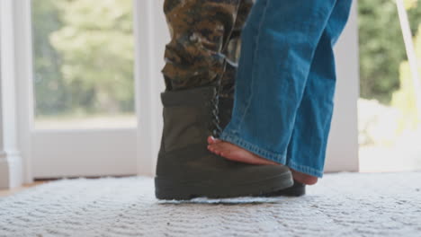 close up of loving army father in uniform home on leave with daughter standing on feet