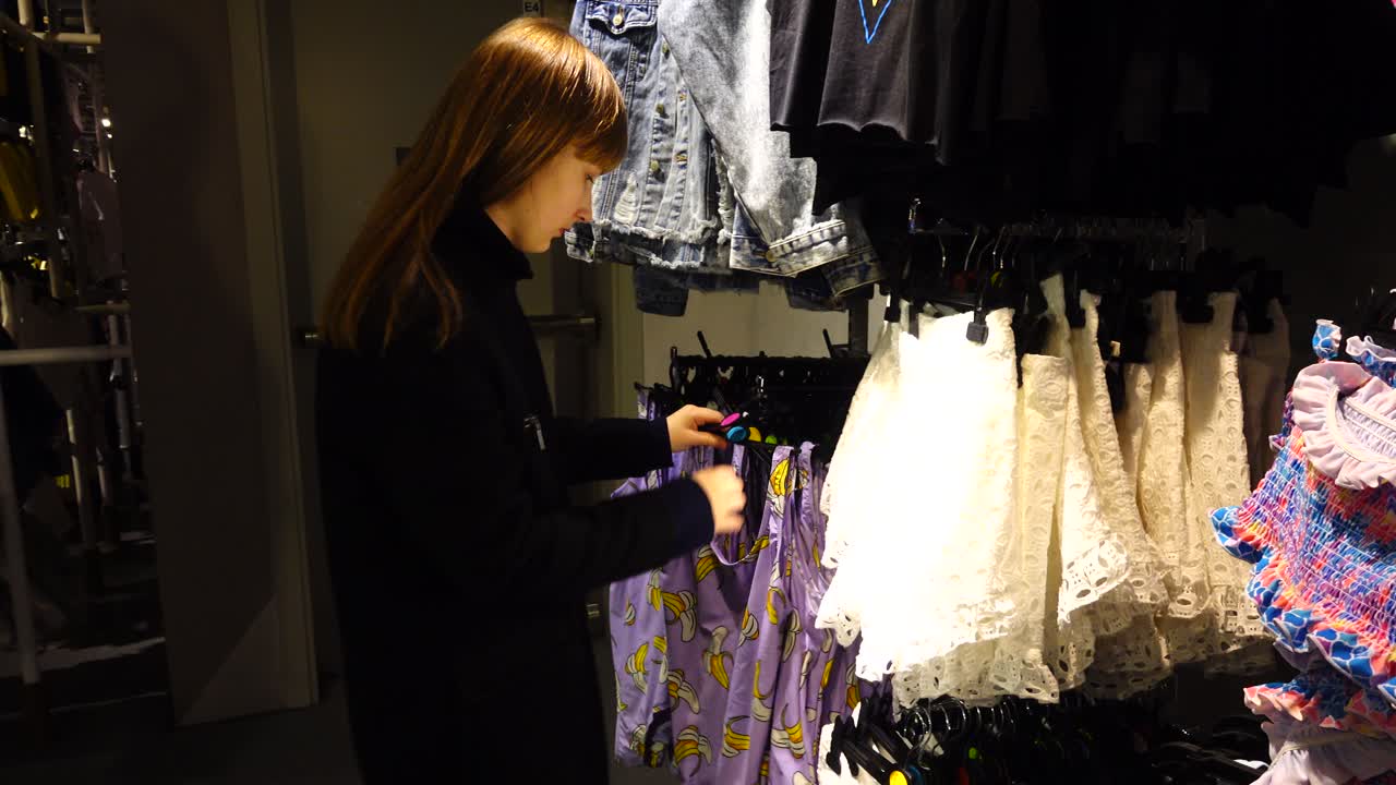 Shopping negli outlet in Europa. La ragazza sceglie i vestiti. Saldi e sconti