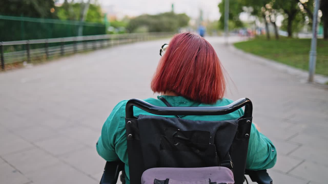 Person with Red Hair Driving Motorized Wheelchair in a Park