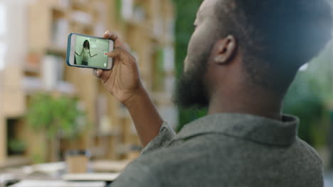 african american businessman using smartphone recording video of boardroom presentation meeting on mobile phone camera sharing question to business woman presenting training lecture close up