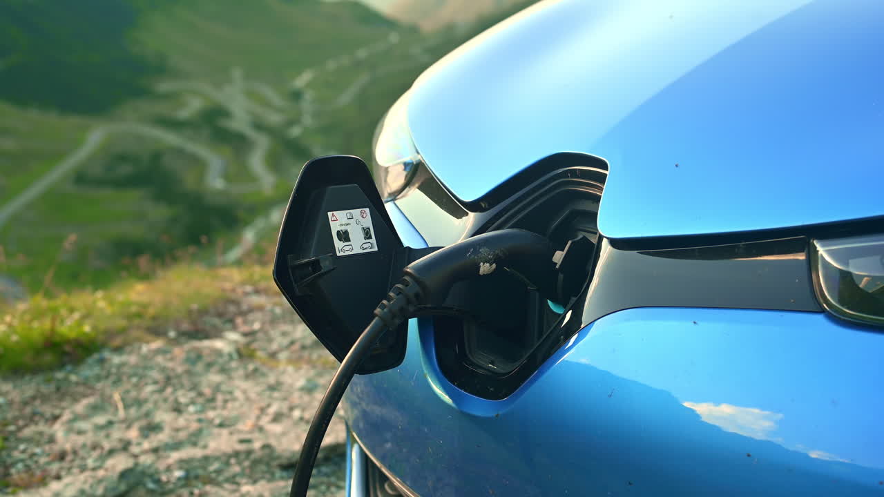 Romanya, Transfăgărășan yolunda elektrikli araba şarj edilirken. Arka planda yeşilliklerle kaplı dağ yamaçlarının bulunduğu yol